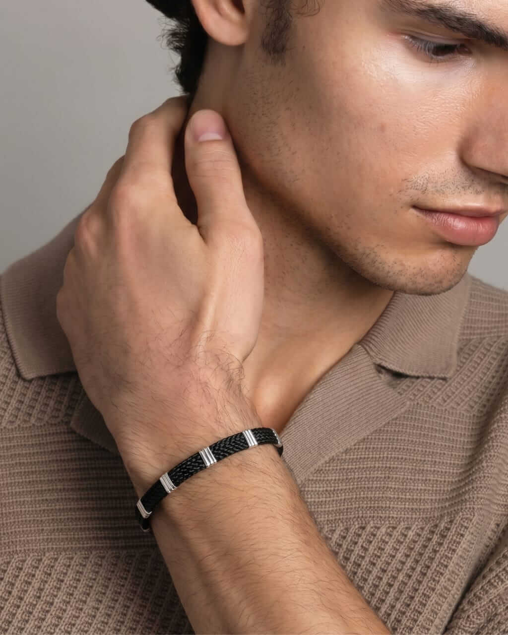 Man wearing Aamani black thread Silver bracelet on his wrist, close-up of hand and arm.
