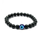 A stylish bracelet featuring black obsidian beads and a single blue evil eye charm at the center.