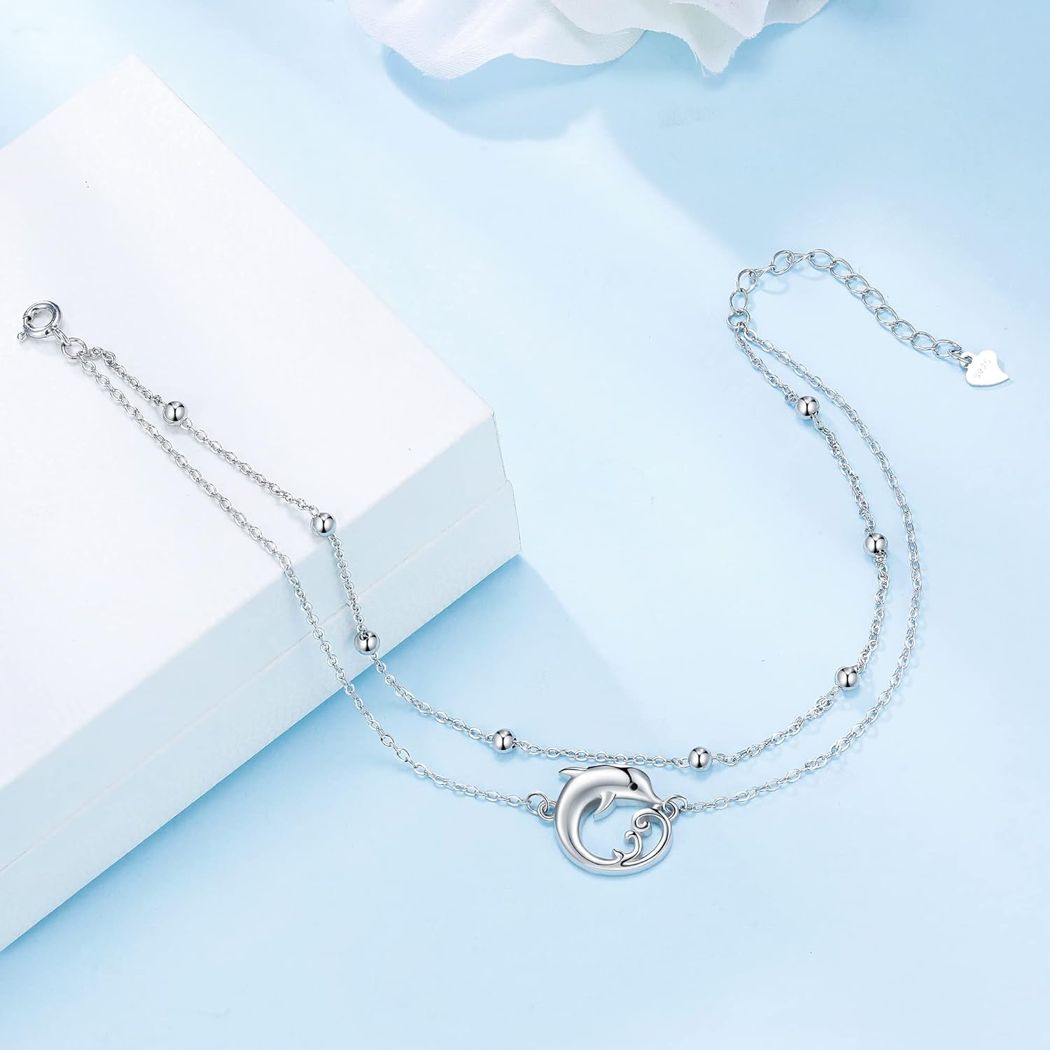 Silver Anklet with a dolphin charm on a light blue background