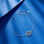 High-polish sterling silver anklet featuring a detailed Tree of Life symbol, styled on a blue textured background.